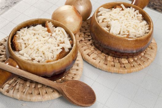 Arrangement of two bowls of onion soup and fresh onions