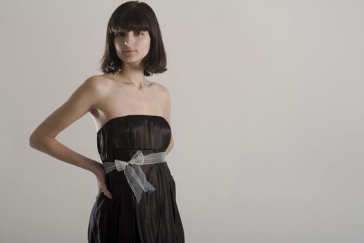 An 18 year old exotic brazilian model, with short dark hair, a young looking face and a skinny body. This was shot in a studio and she's weariing a black, strapless dress. Plenty of copyspace in the image.