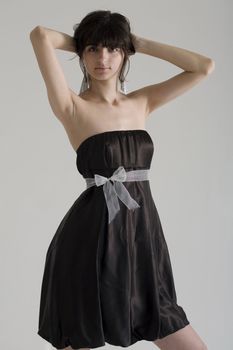 An 18 year old exotic brazilian model, with short dark hair, a young looking face and a skinny body. This was shot in a studio and she's weariing a black, strapless dress.