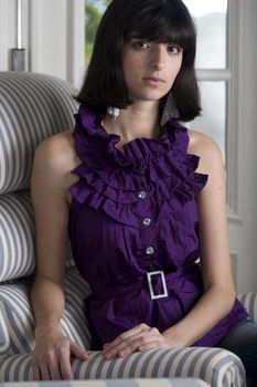 An 18 year old exotic brazilian model, with short dark hair, a young looking face and a skinny body. She is wearing a purple shirt.