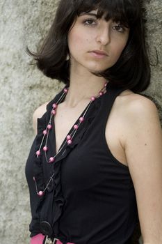 An 18 year old exotic brazilian model, with short dark hair, a young looking face and a skinny body. She is wearing a black dress and pink belt.