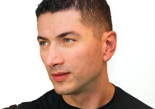 A head shot of a handsome Caucasian man with dark hair and blue eyes wearing black t-shirt isolated over white background.