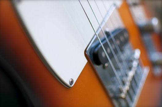 An electric guitar shines in the light of a nearby window.  Shallow depth of field is intentional.