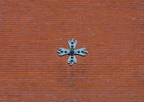 Red Brick wall with steel cross on large city building