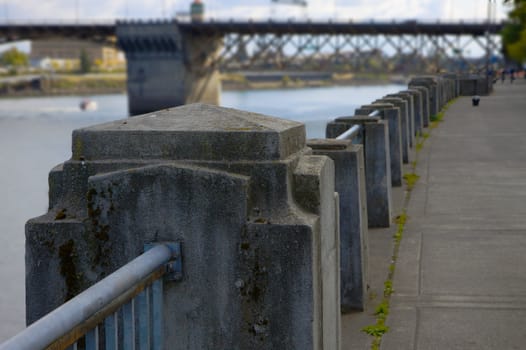 Concrete and Steel Railing near river with soft focus bridge in background