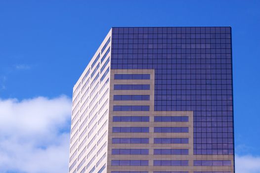 Close up top floors of Skyscraper against a blue nearly cloudless sky 
