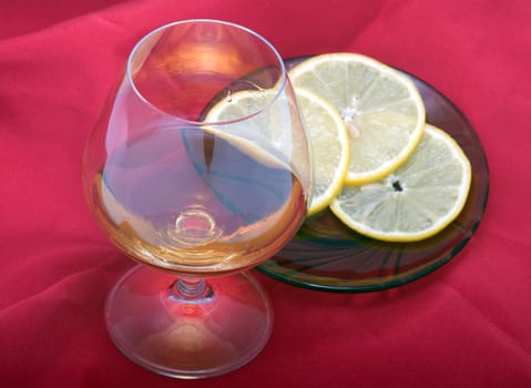 Glass of cognac and lemon segment on a saucer.