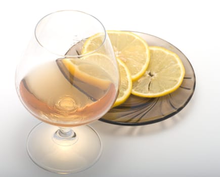 Brandy in a glass and the cut lemon on a saucer.