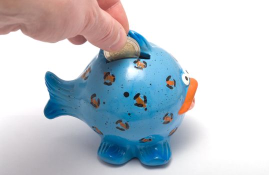 Hand lowering a coin in a coin box in the form of fish.