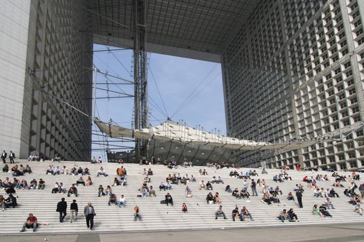 People sitting at lunch time on the steps of the big arch of La Defense in Paris. Picture taken on April 27, 2007.