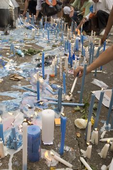Low angle cropped shot of religious candles being lit on the floor.