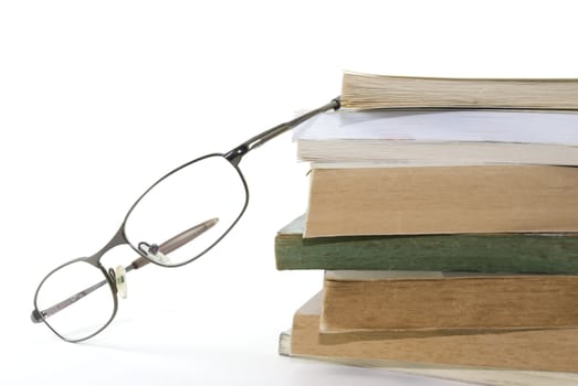 Detail shot of a pair of glasses with stack of books. White background.