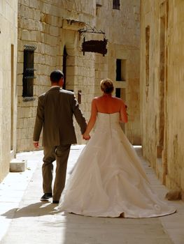 Newly wed couple walking in the old city streets in Malta