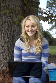 Petty young student on a laptop smiling