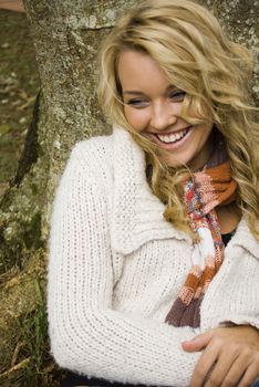 pretty girl leaning on a tree laughing