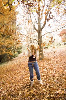 Young girl playing in the Autumn fall leaves