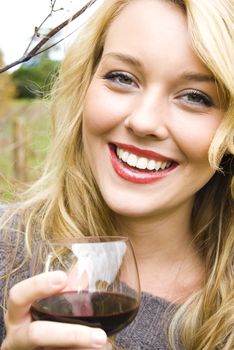 Young pretty girl in a vineyard drinking red wine