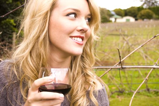 Young pretty girl in a vineyard drinking red wine