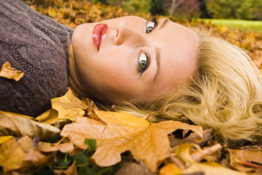 Young girl lying in the Autumn fall leaves