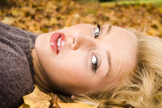 Young girl lying in the Autumn fall leaves