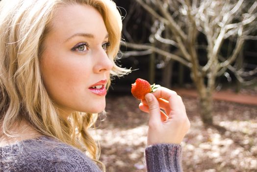 Over should angle of a pretty young woman about to take a bite of a fresh strawberry