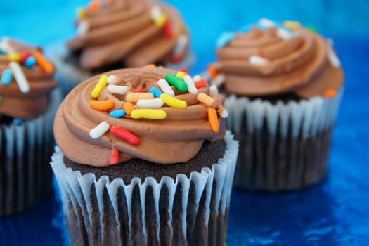 chocolate frosted cupcakes on a metallic blue background