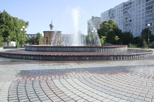 Fountain in the city with church on the background.