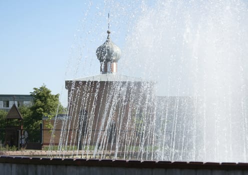 Fountain in the city with church on the background.