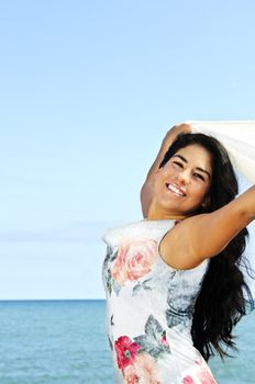 Portrait of beautiful smiling brunette girl at beach with arms outstretched