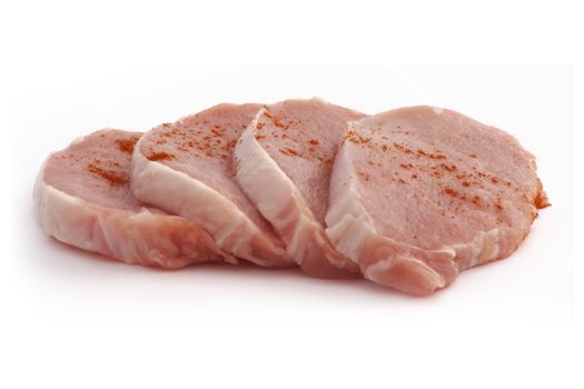 four pieces of raw pork on a white background