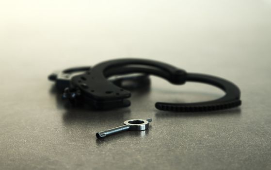 Handcuffs open on table with key in foreground