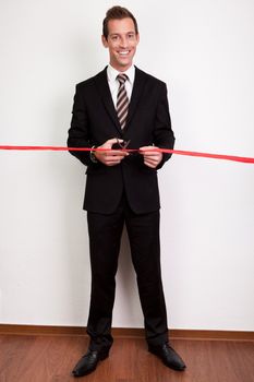Businessman cutting a red tape against white background