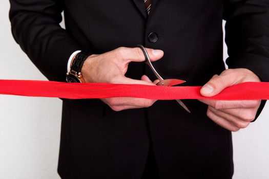 Businessman cutting a red tape against white background