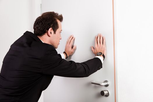Businessman pushing the door to prevent people entering room