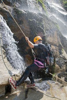 Men descending in rappeling a waterfall