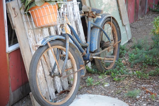 A vintage bike leaning against a wall outdoors.