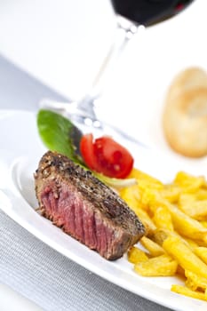 closeup of a beef steak with french fries on a white background