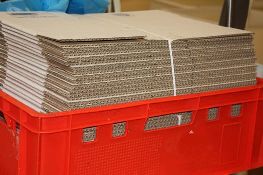 Stack of unfolded cardboard boxes in red storage crate