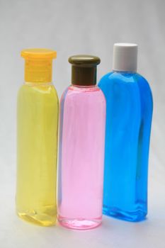 Three different shaped shampoo bottles in yellow, pink and blue