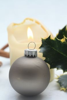 A grey christmas ornament with a burning candle on background