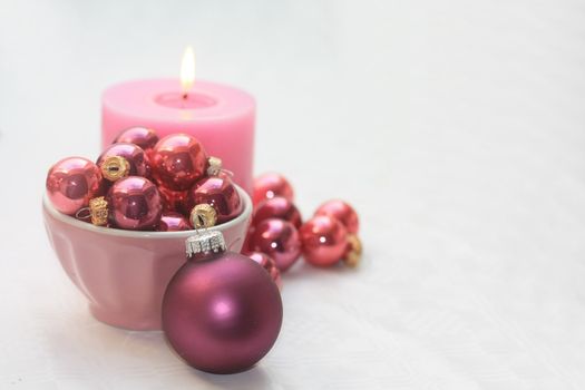 Pink christmas decorations and pink candle on white background