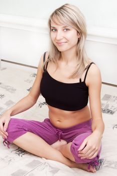 Beautiful young woman doing meditation on the bed