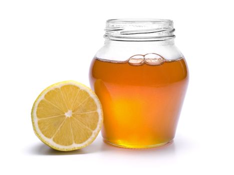 A jar of honey and a lemon. Isolated on white background.