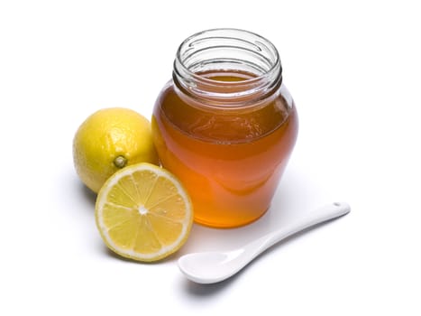 A jar of honey, lemons and spoon. Isolated on white background.