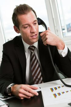 Young businessman speaking on the phone at workplace