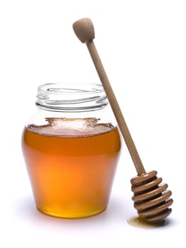 Jar of honey with a wooden drizzler a side. Isolated on white background.