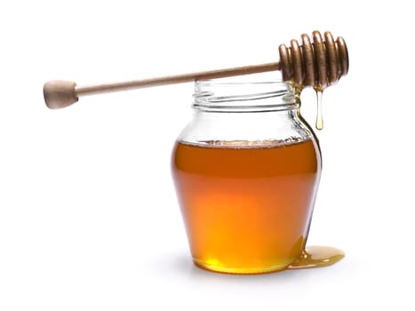 Jar of honey with a wooden drizzler on top. Isolated on white background.