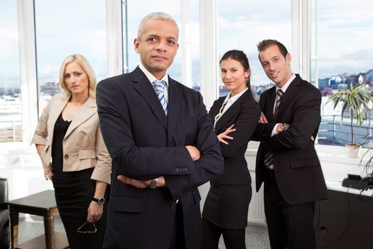 Businessman standing in front. Three business colleagues working in background.