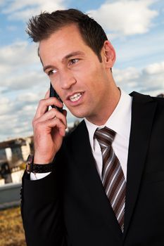 Portrait of businessman talking on cellphone outside