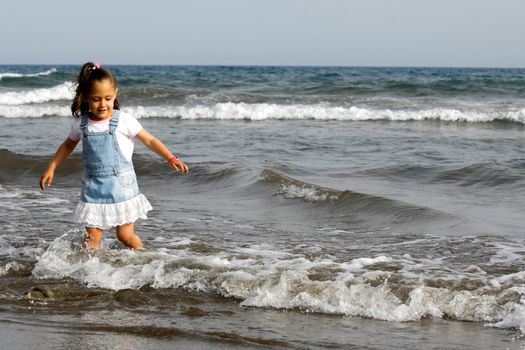 Child is standing in the big ocean alone.